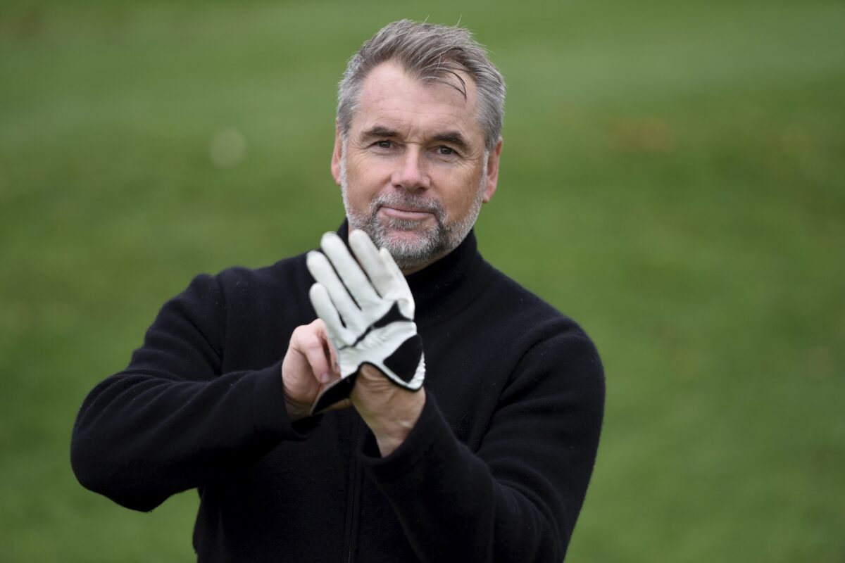 Fußballtrainer Bernd Hollerbach zieht sich seinen Golfhandschuh an